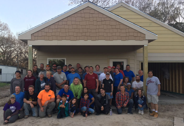 A working mom and three children (bottom center) with church volunteers and community leaders in front of the family’s new home in Houston. AmeriLife’s Gregg Barfield is pictured at far right.